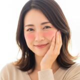 頬に手を当てて少し顔を赤らめている女性