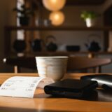 テーブルの上に置かれた伝票と財布、またはカードリーダー