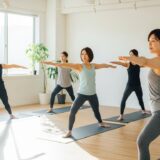 複数の女性がマットの上でヨガまたはピラティスのポーズをしている様子